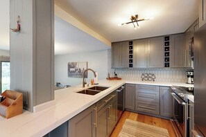 A modern kitchen with grey cabinets, a white countertop, and stainless steel appliances. - Gorgeous mountain retreat with pool, hot tub, games, & golf - walk-to-lifts (Sun Valley)