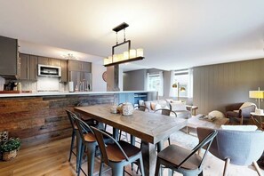 A modern kitchen with a central island, bar stools, and a dining table. - Gorgeous mountain retreat with pool, hot tub, games, & golf - walk-to-lifts (Sun Valley)