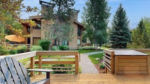 A modern building with a wooden deck, a bench, and a pathway leading to the entrance. - Charming condo with WiFi, deck, fireplace, shared pool, hot-tub, and sauna (Sun Valley)