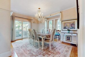 A dining room with a chandelier, a large window, and a fireplace. - Beautifully renovated home walk to boulevard, town & train (Gloucester)