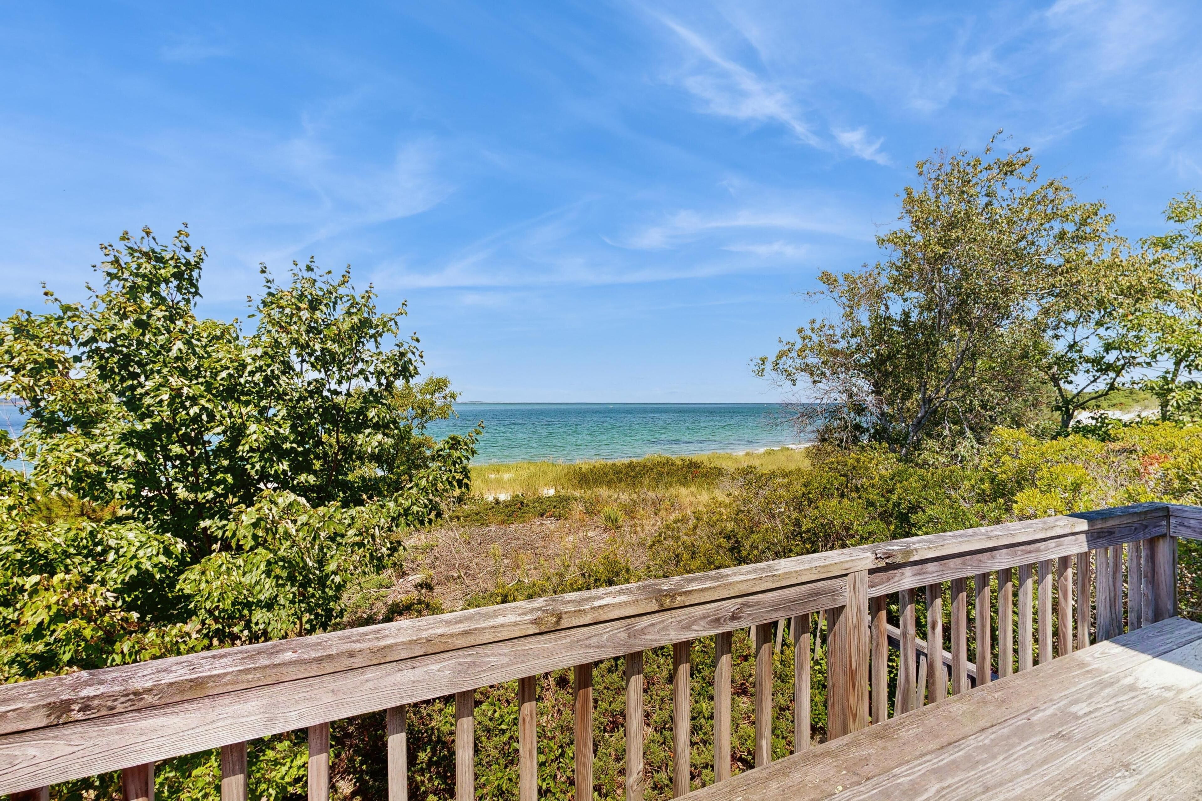 A wooden deck overlooking a beach with clear skies.