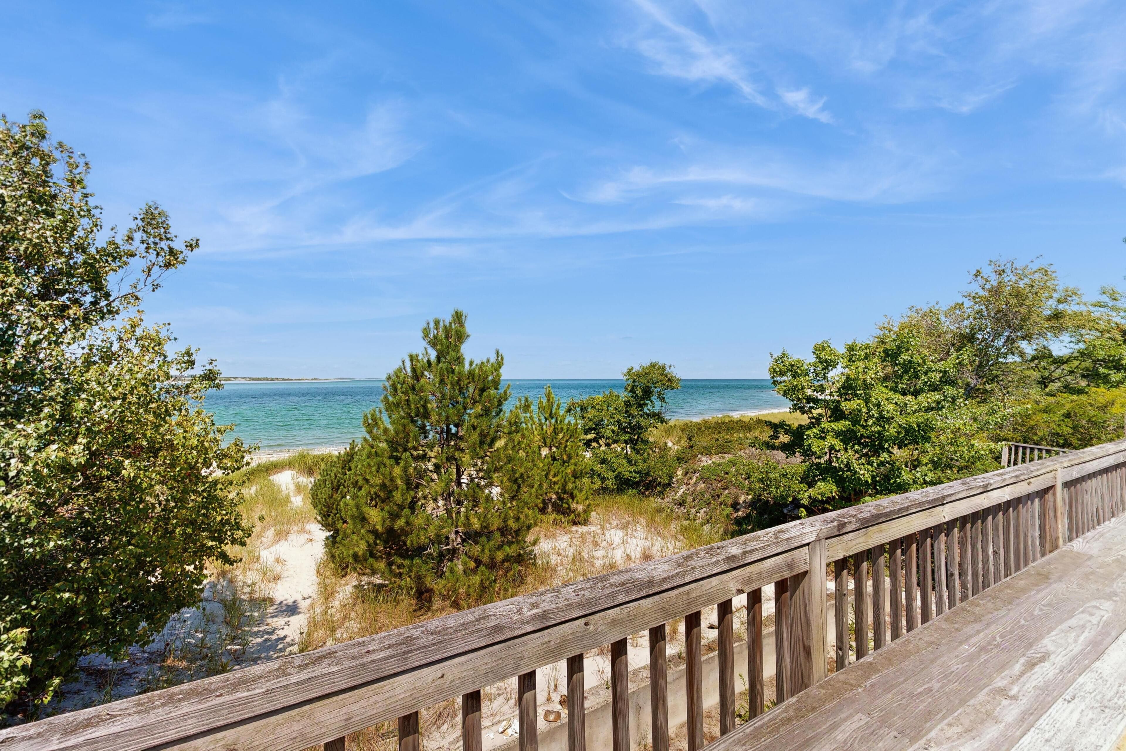 A wooden deck overlooking a beach with clear skies.
