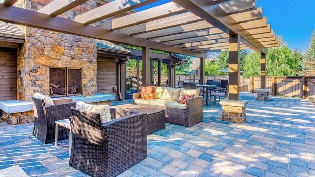 An outdoor patio with stone walls, a fire pit, wicker furniture, and a pergola. - Cozy ski condo with patio, fireplace, WiFi, shared pool & hot tub, walk to lifts (Sun Valley)