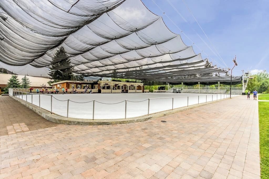 A covered outdoor area with a paved walkway, a fence, and a building with a sign.