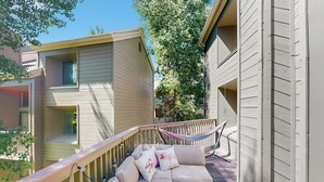 Un balcon doté d’un espace salon avec des coussins, d’un hamac et offrant une vue sur les bâtiments voisins.