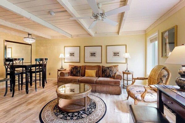 A living room with a wooden ceiling, a round coffee table, a sofa, a dining table with chairs, and framed pictures on the wall. - Cozy Sun Valley condo, walk to village, skiing and mountain adventures (Sun Valley)