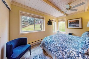 A bedroom with a bed, a chair, a ceiling fan, and a window with a view of the outdoors. - Cozy Sun Valley condo, walk to village, skiing and mountain adventures (Sun Valley)