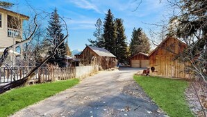 Eine ländliche Straße mit Hollerntscheuern, einem eingezäunten Hof und einem Haus.