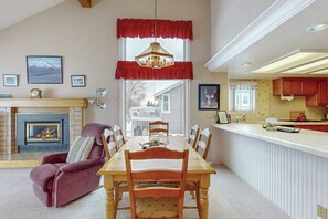 A dining area with a fireplace, a chandelier, and a view of the outside. - Spacious Dog-Friendly Condo on the 7th Hole of Eagle Bend Golf Course (Bigfork)