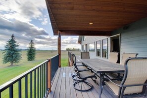 Eine überdachte Terrasse mit Gartenmöbeln, Blick auf die Landschaft und ein Gebäude mit großen Fenstern.