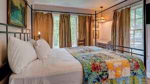 A bedroom with a bed, a painting, and curtains.