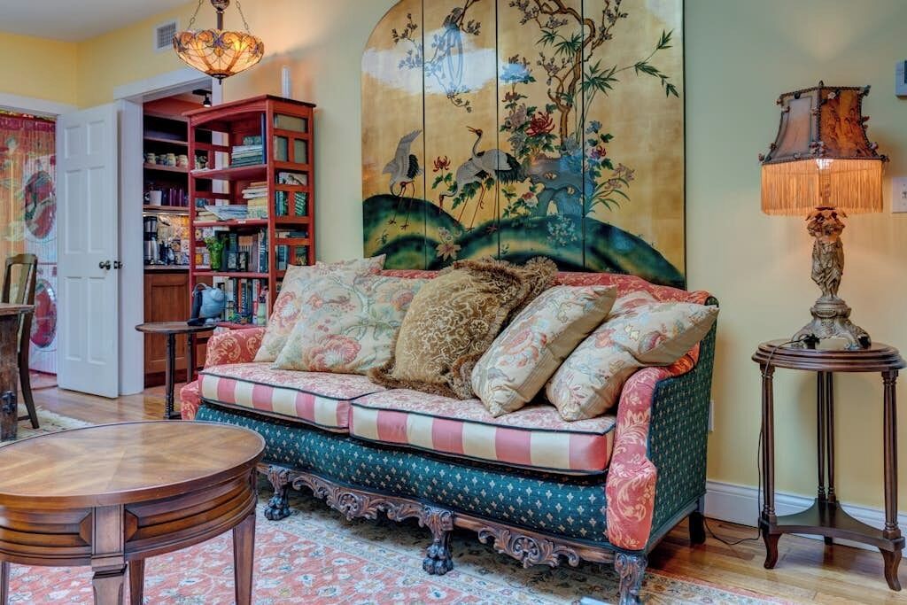Un salon chaleureux avec un canapé, une table ronde en bois, une bibliothèque et une lampe décorative.