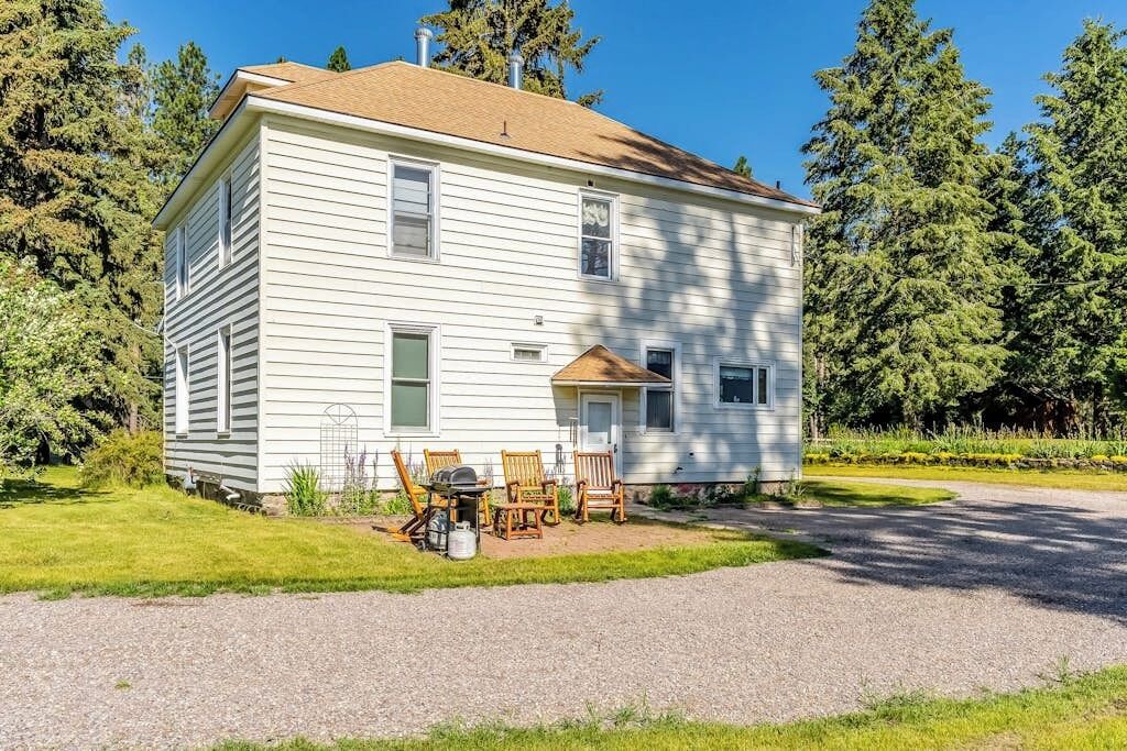 Une maison à deux étages avec un porche à l’avant, une allée en gravier et un petit jardin agrémenté de meubles d’extérieur.