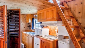 A compact kitchen with wooden cabinets, a microwave, a stove, and a sink. - Waterfront home on Echo Lake with dock, amazing view, deck & washer/dryer (Bigfork)