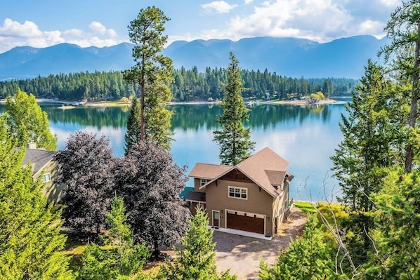 Ein Haus mit Garage, umgeben von Bäumen und einem See.