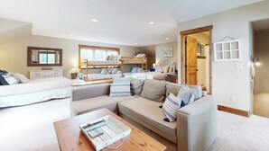 A spacious room with a bed, a sofa, a coffee table, and a bunk bed. - Waterfront home on Echo Lake with dock, amazing view, deck & washer/dryer (Bigfork)
