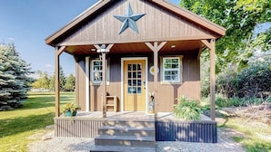 A wooden cabin with a star-shaped roof, a front door, and a small porch with steps. - Rustic getaway with fireplace, patio area, board games, full kitchen, & TV (Kalispell)