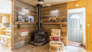 A cozy room with a wood-burning stove, a chair, and shelves with pictures.