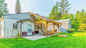 A single-story mobile home with a covered patio area, a small attached garage, and a well-maintained lawn.