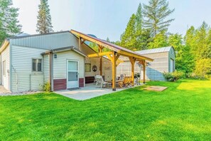 Ein Bungalow mit einer überdachten Terrasse, einer kleinen angeschlossenen Garage und einem gepflegten Rasen.
