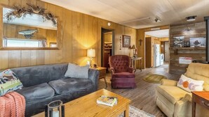A cozy living room with a leather sofa, a red armchair, and a wooden coffee table.