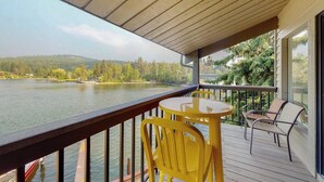 Eine Holzterrasse mit Tisch und Stühlen mit Blick auf einen See.