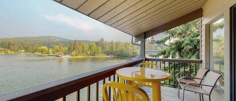 A wooden deck with a table and chairs overlooking a lake.