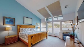 Ein Schlafzimmer mit einem Holzbett, einem Heizkörper, einem Schreibtisch und großen Fenstern.