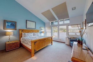 A bedroom with a wooden bed, a radiator, a desk, and large windows. - Lakefront condo with balcony, stunning views, fast WiFi & W/D (Bigfork)