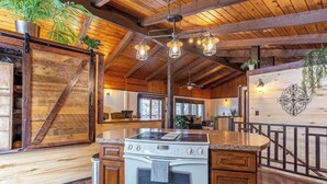 Una cocina rústica con vigas de madera, una isla central e iluminación colgante.