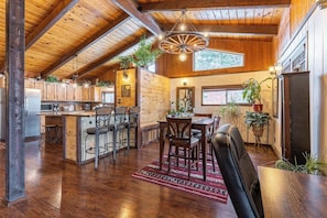 A spacious kitchen with wooden cabinets, a dining area with a red rug, and a large window. - Lake & mountain view retreat with washer/dryer, & furnished deck (Bigfork)