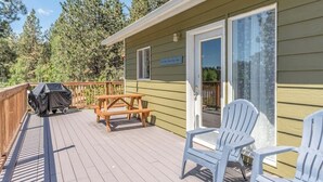 Une terrasse équipée d’un barbecue, d’une table de pique-nique et de chaises Adirondack.