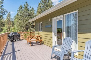 Eine Terrasse mit Grill, Picknicktisch und Adirondack-Stühlen.