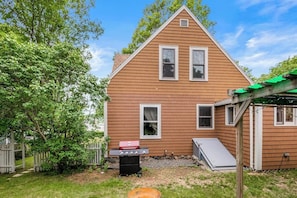 A two-story house with a covered patio, a barbecue grill, and a small shed. - Home with washer/dryer, gas grill, & outdoor dining - walk 5 minutes to beach (Rockport)
