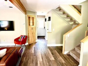 Ein Wohnzimmer mit einem roten Sessel, einem Fernseher und einer Treppe.
