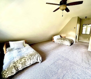 Een slaapkamer met twee bedden, een plafondventilator en een vloerbedekking.