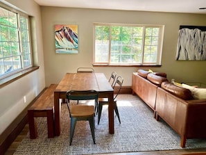 Een eethoek met een houten tafel en stoelen, een bank en kunstwerken aan de muur.