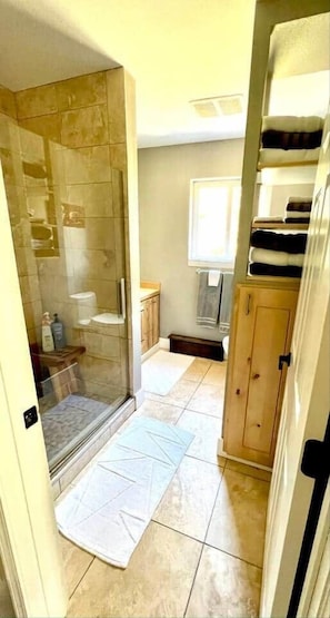 Een badkamer met een douchecabine van glas, een toilet, een wastafel en een kast.