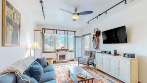 Ein Wohnzimmer mit einer Couch, einem Fernseher, einem Kamin und einem gemusterten Teppich.