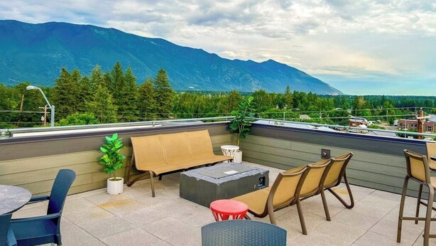 Eine Dachterrasse mit Sitzgelegenheiten, einer Feuerstelle und Blick auf Berge.