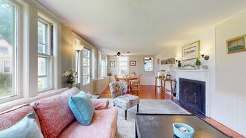 A living room with a sofa, a coffee table, a fireplace, and a dining area with chairs and a table.