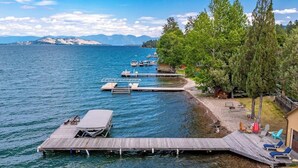 Un muelle a orillas del lago con barcos, un espigón de madera y asientos al aire libre.
