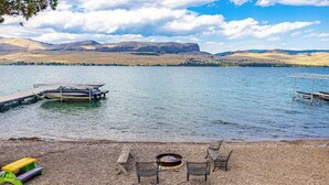 Un entorno junto al lago con un muelle, una fogata y asientos.