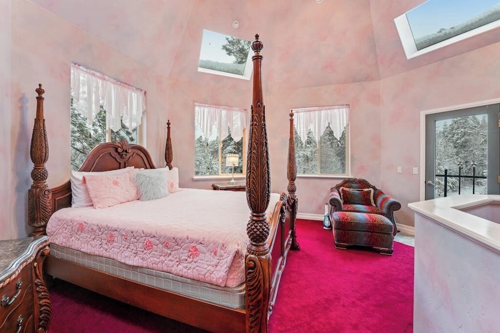 Une chambre à coucher avec un lit à baldaquin, une chaise longue, une grande fenêtre et une lucarne.