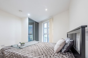 Ein Schlafzimmer mit einem Bett, einem Fenster und einer Tür zu einem anderen Raum.