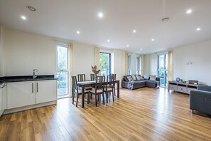 Ein geräumiger Wohnbereich mit Esstisch, Sofa und Küchenzeile mit Schränken und Arbeitsplatte.