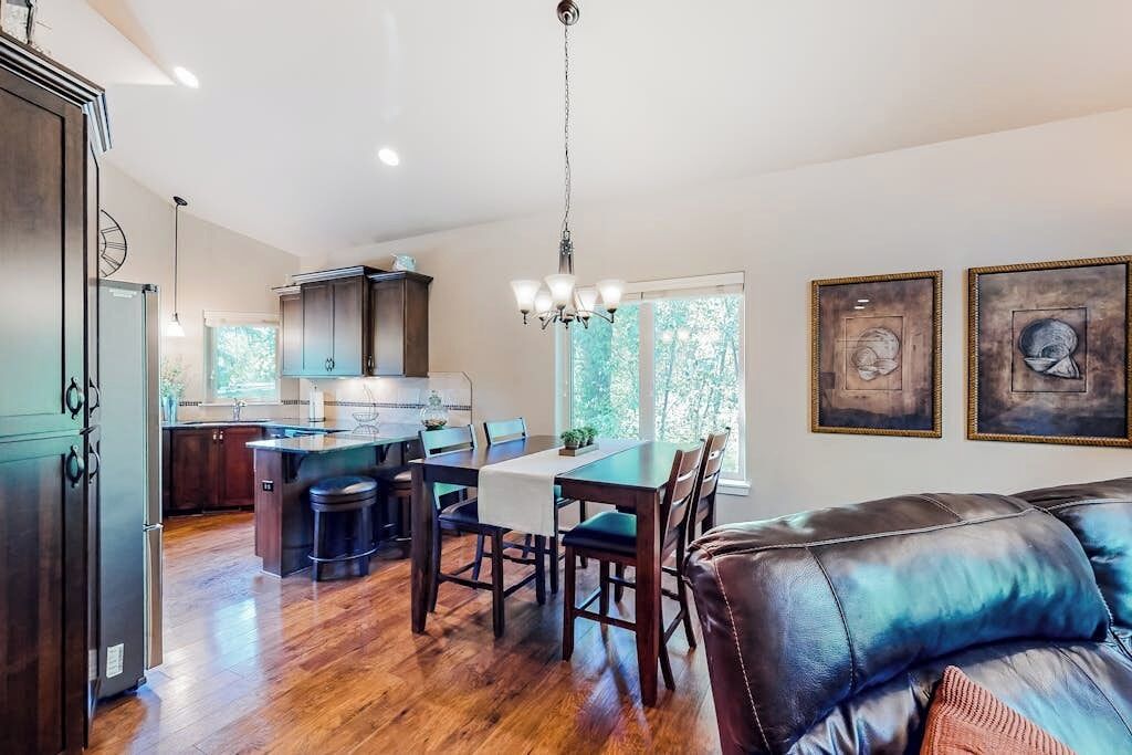 A spacious kitchen with a dining area, a leather sofa, and artwork on the walls.