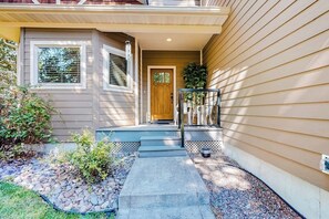 A house with a front porch, a wooden door, and a small garden area with steps leading to the entrance.