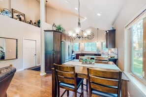 A spacious kitchen with a large island, dark wooden cabinets, and a chandelier.