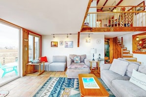 Ein geräumiges Wohnzimmer mit hoher Decke, einer Treppe und einem großen Fenster.